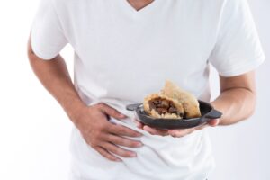 IMAGE OF SOMEONE HOLDING A BOWL OF FOOD AND CLUTCHING THEIR STOMACH BECAUSE OF FOOD POISONING