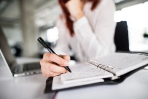 A solicitor in a white blouse sits at a desk with a notebook answering the question "what is a litigation friend?".