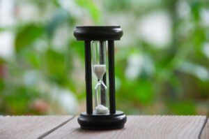 A sand time sitting on a wooden table outside
