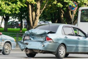 A light blue car what has a damaged boot. 