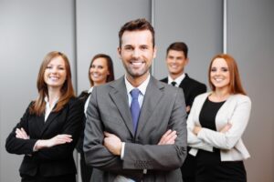 A team of lawyers stand smiling with their arms folded, ready to fight for domestic abuse compensation.