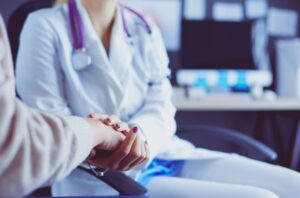 A doctor holds a patient's hand. 
