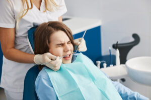 A child undergoes dental work with discomfort visible on their face.