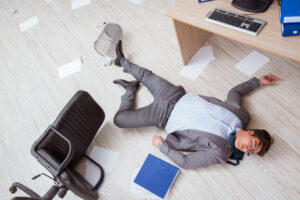 A businessman has had an office accident is lying on the floor.