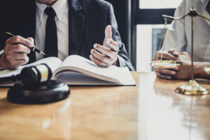 Solicitors at a desk with a set of justice scales and a gavel examining After The Event insurance policies for their client