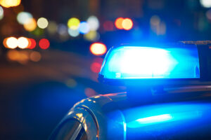 Blue lights on a police car at the scene of a criminal injury at night.