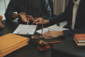 Two knee injury claims solicitors sat at a desk with a gavel, legal documents, and set of justice scales. 