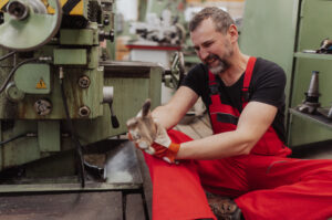 A worker in red overalls holds his injured wrist.