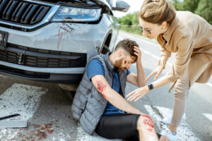 A woman helps a pedestrian who has suffered soft tissue injuries and minor fractures in a car accident.
