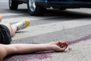 A body lays in the street after being hit by a car.
