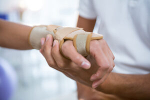 A doctor holds the bandaged hand of a patient.