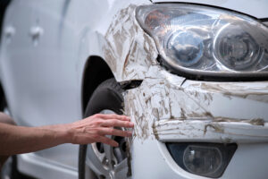 A man examines the damage on his car headlight after an accident
