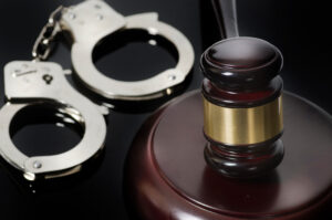 A gavel and set of handcuffs on a black table. 