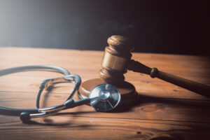 A stethoscope and a gavel on an oak table alongside each other to represent death by medical negligence claims. 